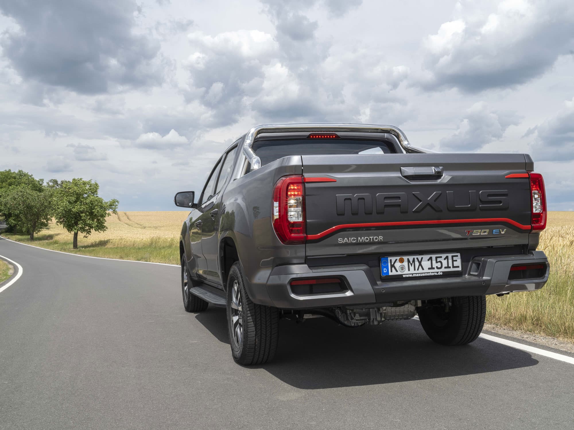 Maxus T90 EV Grijs achteraanzicht tussen velden